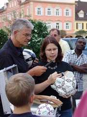 Birgit Felgentreu vom Weltladen Ludwigsburg erklärt dem Publikum und Stadtrat Siegfried Rapp wie Fussbälle gemacht werden